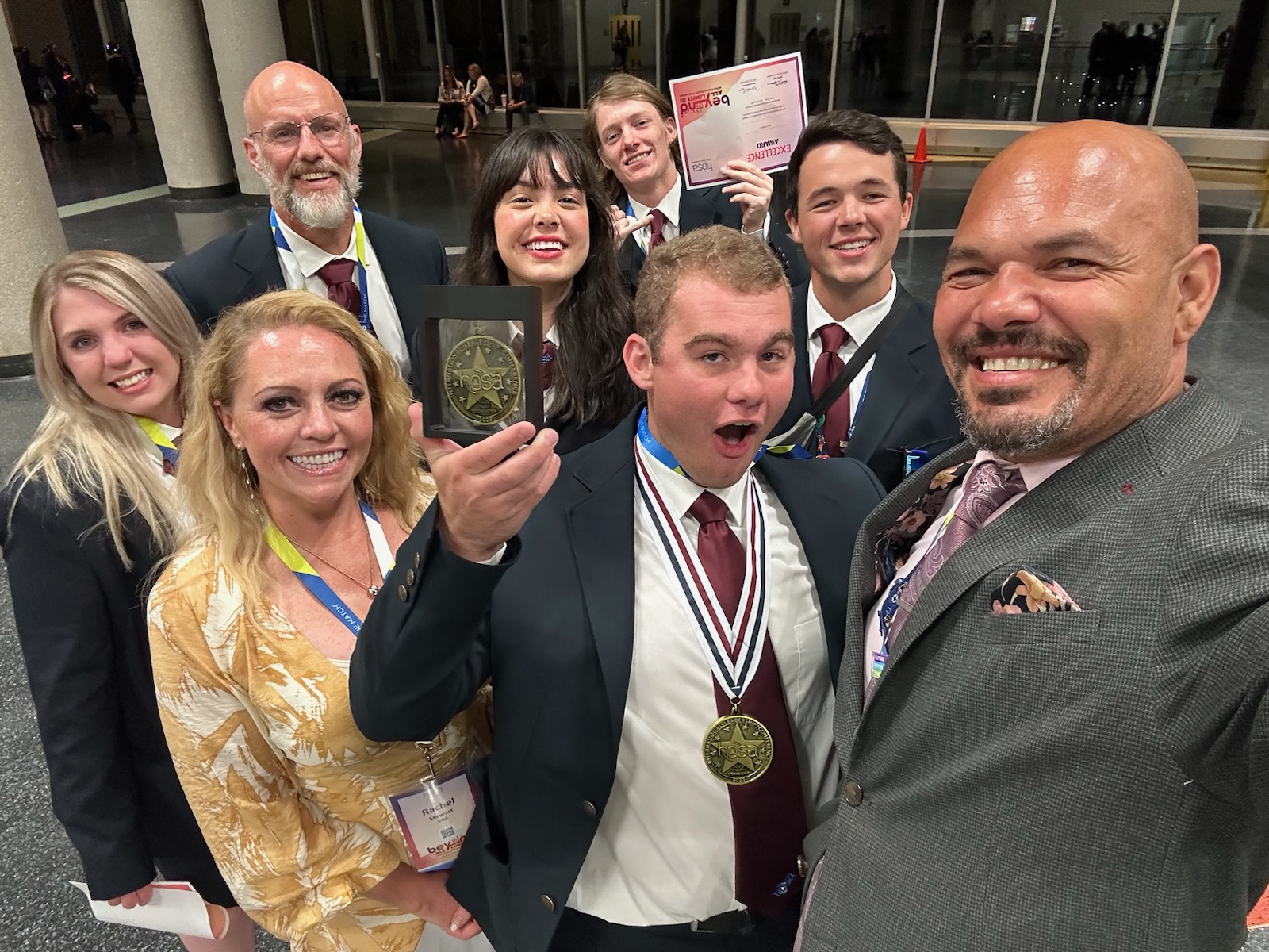 Students and instructors celebrate HOSA awards, holding a medal and certificate.