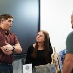 A photo of a man and woman talking to someone at a booth