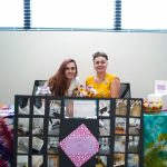 two women posing at a booth