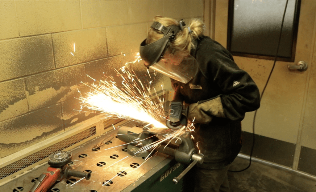 a student grinding a piece of metal with a power tool.