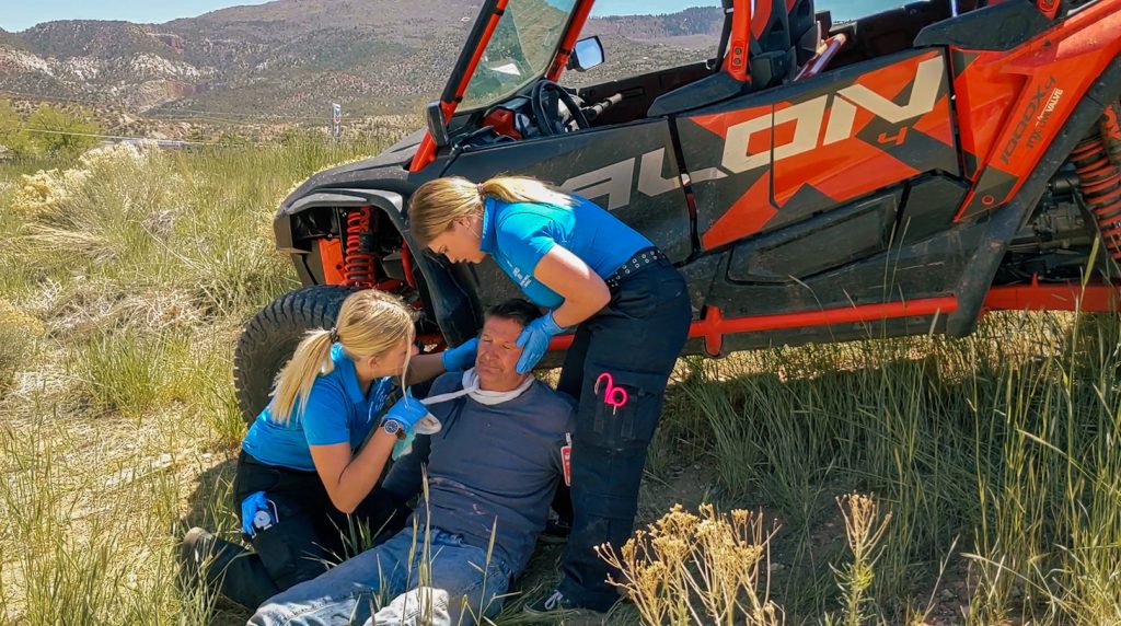 public safety students administering aid to a simulated victim next to an offroad vehicle.